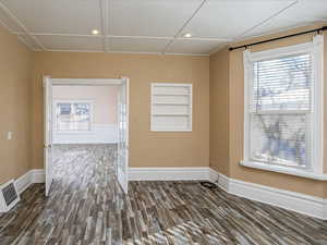 Unfurnished room featuring built in shelves, dark wood-style floors, healthy amount of natural light, and recessed lighting