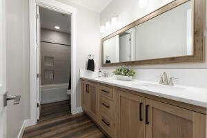 Full bathroom with double vanity, dark wood-style floors, and shower / tub combination