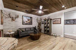 Living room with ceiling fan, wood finished floors, and wooden ceiling