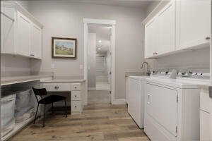 Laundry area with cabinet space, washing machine and clothes dryer, light wood-style flooring, and an office area