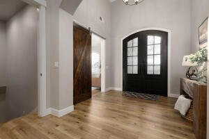 Entrance foyer with arched walkways, a barn door, light wood-style flooring, french doors, and a high ceiling