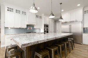 Kitchen with glass insert cabinets, white cabinetry, a breakfast bar area, backsplash, and built in fridge