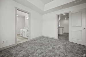 Unfurnished bedroom with ensuite bathroom and light colored carpet
