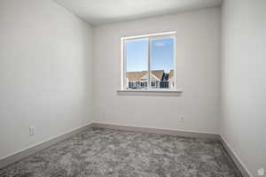 Carpeted spare room featuring baseboards