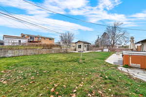 Fenced backyard with a hot tub, a patio, and an outdoor structure