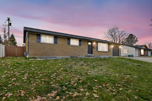 Single story home featuring brick siding, a garage, and a patio area