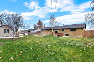 Rear view of property with a hot tub, a patio, brick siding, and a fenced backyard