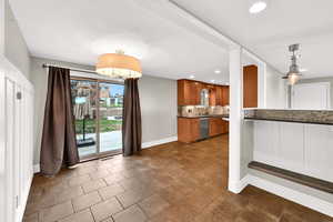 Kitchen with brown cabinets, backsplash, decorative light fixtures, recessed lighting, and dishwasher