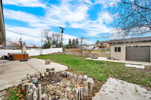 Fenced backyard featuring a patio area, a hot tub, and a fire pit