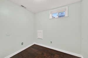 Spare room with a textured ceiling and dark wood-style floors
