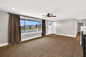 Unfurnished living room with recessed lighting, dark carpet, a mountain view, and a ceiling fan