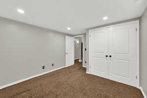 Unfurnished bedroom with a closet, dark carpet, and recessed lighting