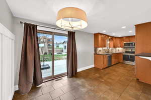 Kitchen featuring stainless steel appliances, a chandelier, brown cabinets, recessed lighting, and pendant lighting