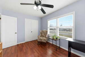 Living area featuring dark wood-style floors and ceiling fan