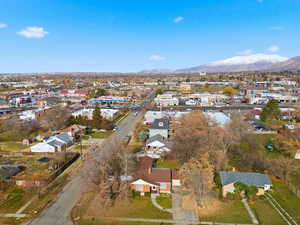Aerial view of property and surrounding area featuring mountains and nearby suburban area