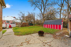 View of yard featuring an outdoor fire pit and a storage shed