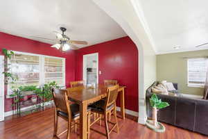 Dining room with a ceiling fan, arched walkways, and dark wood-type flooring