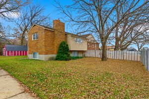 View of property exterior with a chimney, a yard, and brick siding