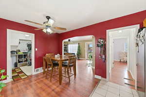 Dining area featuring arched walkways, ceiling fan, and light wood-style floors
