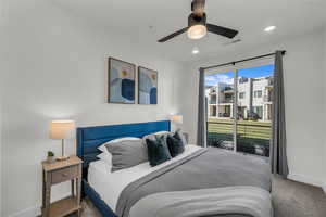 Bedroom with carpet, ceiling fan, and access to outside through large sliding door.