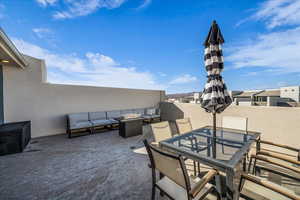 View of patio with an outdoor living space with a fire pit and outdoor dining space on roof top patio.