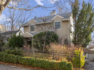 Traditional home with a fenced front yard, stucco siding, and a shingled roof