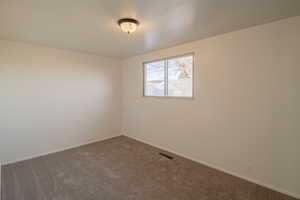 Carpeted spare room featuring baseboards