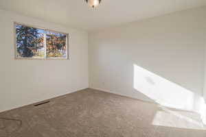 Carpeted spare room featuring baseboards