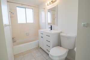 Bathroom featuring shower / bathtub combination, vanity, and light tile patterned floors