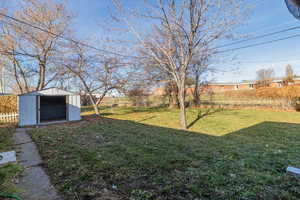 Fenced backyard featuring a storage shed