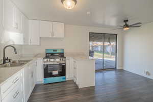Kitchen with stainless steel range with electric cooktop, a peninsula, dark wood-type flooring, and white cabinetry