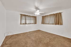 Carpeted empty room with baseboards and a ceiling fan