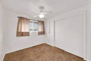 Unfurnished bedroom with a closet, carpet flooring, and a ceiling fan
