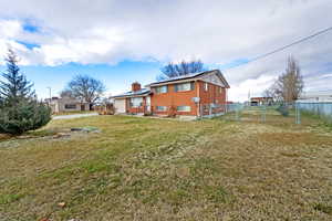 Back of house with solar panels, a chimney, and a gate