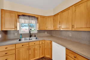 Kitchen featuring dishwasher, light countertops, decorative backsplash, and light brown cabinetry