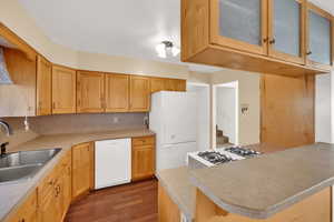 Kitchen with white appliances, light countertops, dark wood-style floors, and light brown cabinets