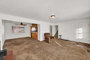 Unfurnished room with carpet flooring, ceiling fan, and stairway