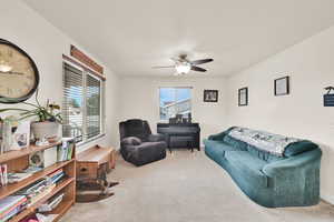 Living area with light carpet and ceiling fan