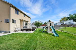 Fenced backyard featuring a playground and a patio