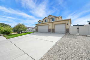 Traditional-style home with a gate, driveway, a garage, stucco siding, and brick siding