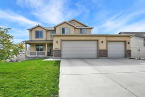 Traditional-style home with stucco siding, covered porch, driveway, a gate, and brick siding