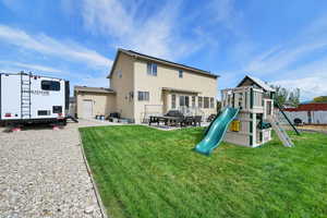 Rear view of property featuring a patio area, a lawn, stucco siding, and a playground