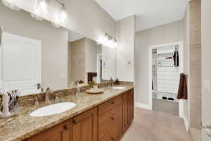 Full bathroom featuring double vanity, light tile patterned floors, and a spacious closet