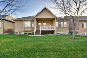 View of front of house featuring stucco siding, a front lawn, and a porch