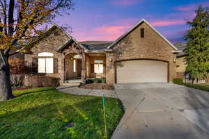 View of front facade featuring brick siding, a front yard, concrete driveway, and a garage