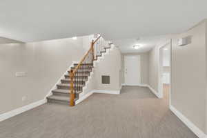 Entrance foyer featuring stairs and light carpet