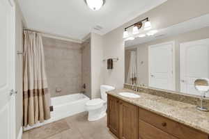 Bathroom featuring shower / bath combo with shower curtain, vanity, and light tile patterned floors