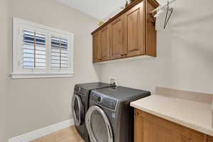 Washroom with washing machine and dryer, cabinet space, and light tile patterned floors