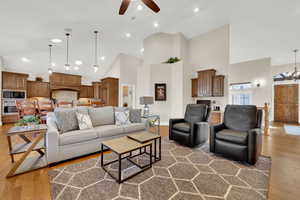 Living room with high vaulted ceiling, a chandelier, light wood-type flooring, and a ceiling fan