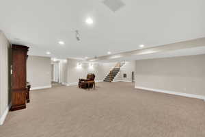 Finished basement featuring stairway, recessed lighting, and light colored carpet